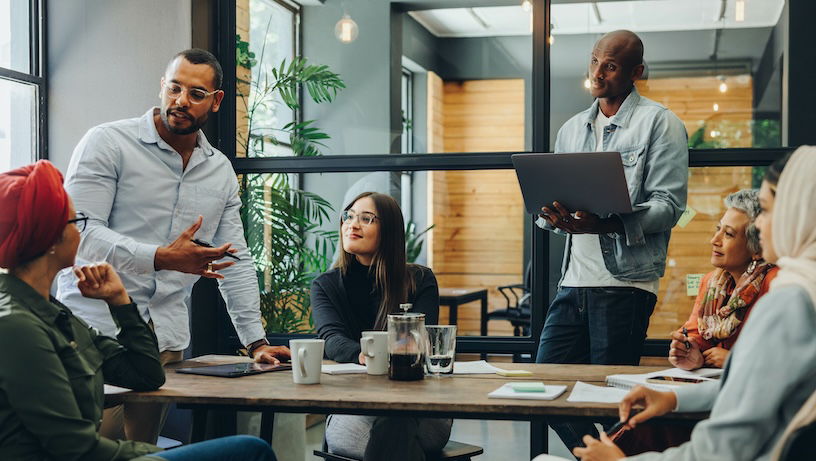 Creative Communication and Technology professionals having a group discussion during a meeting in a modern office. Team of multicultural businesspeople sharing ideas in an inclusive workplace.