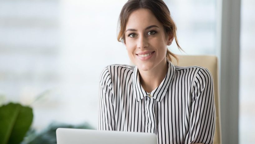Portrait of smiling beautiful millennial businesswoman or CEO looking at camera, happy female boss posing making headshot picture for company photoshoot, confident successful woman at work