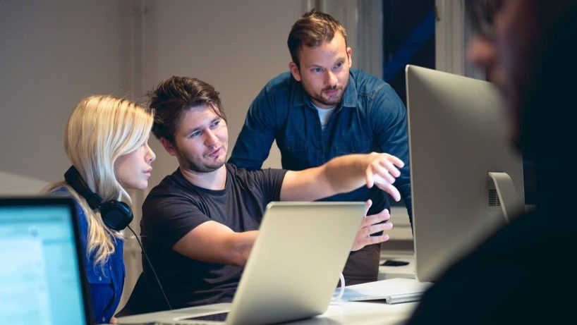 Mobile Development professionals looking at mockups on a desktop computer.
